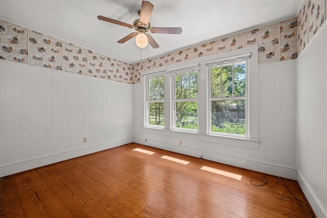 unfurnished room with baseboards, wallpapered walls, ceiling fan, and hardwood / wood-style flooring