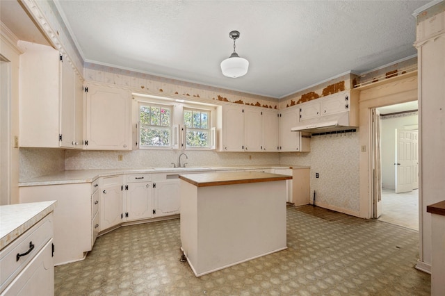 kitchen with light floors, a kitchen island, a sink, under cabinet range hood, and a textured ceiling