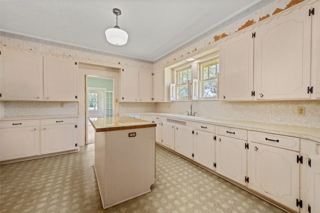 kitchen with light floors, ornamental molding, a healthy amount of sunlight, and a sink