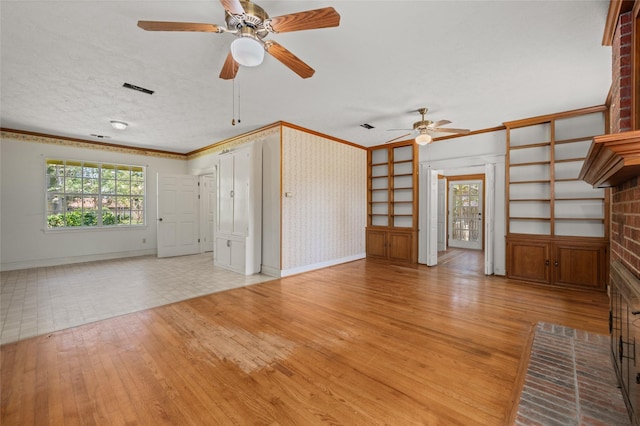 unfurnished living room featuring baseboards, ornamental molding, ceiling fan, hardwood / wood-style flooring, and a textured ceiling