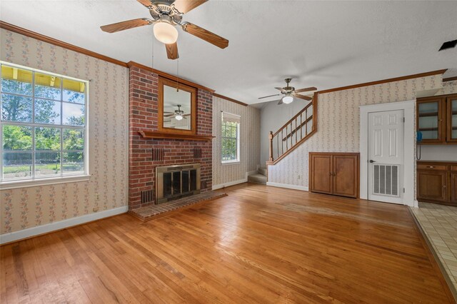 unfurnished living room with ceiling fan, visible vents, ornamental molding, and wallpapered walls