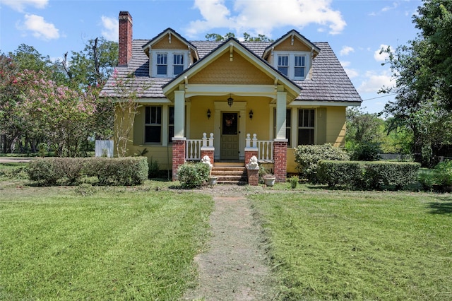 view of front of house with a porch, a chimney, and a front lawn