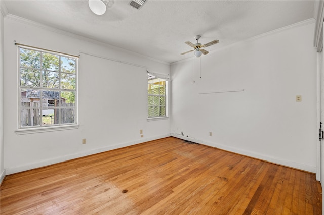 empty room with crown molding, a ceiling fan, visible vents, and light wood-type flooring