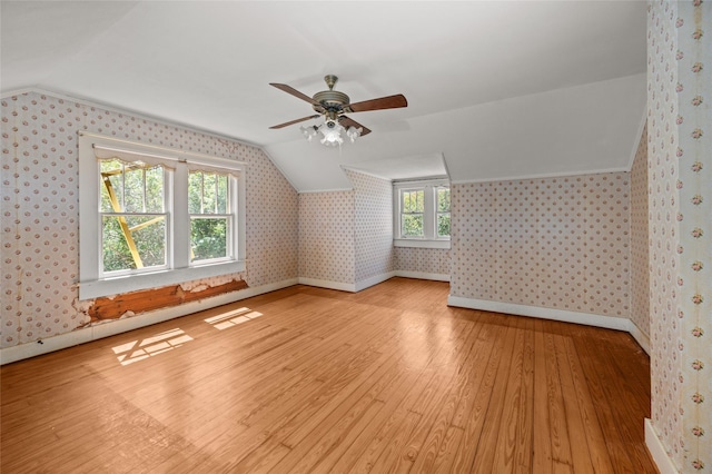additional living space with lofted ceiling, hardwood / wood-style flooring, ceiling fan, and wallpapered walls