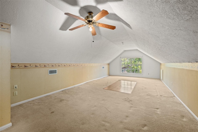 additional living space with visible vents, a ceiling fan, a textured ceiling, carpet, and vaulted ceiling