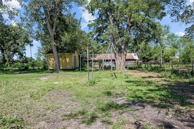 view of yard with an outbuilding, a shed, a playground, and a fenced backyard