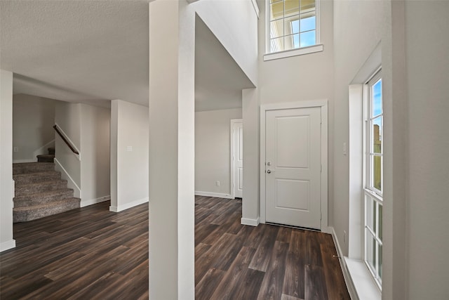 entryway featuring dark wood-type flooring, a textured ceiling, and a high ceiling