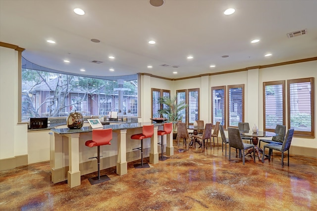 kitchen with crown molding, white cabinetry, and a kitchen breakfast bar