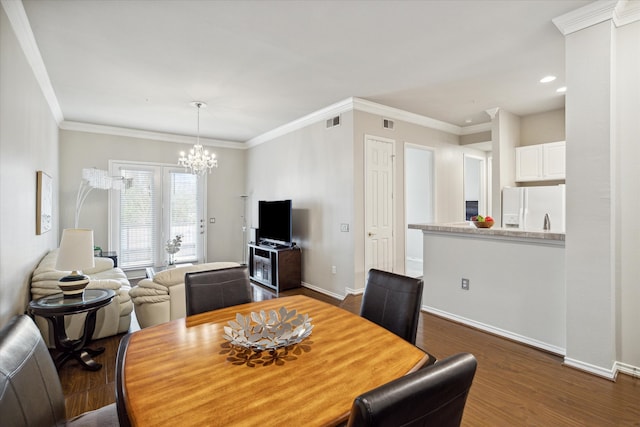 dining space featuring ornamental molding, dark wood-type flooring, and a notable chandelier