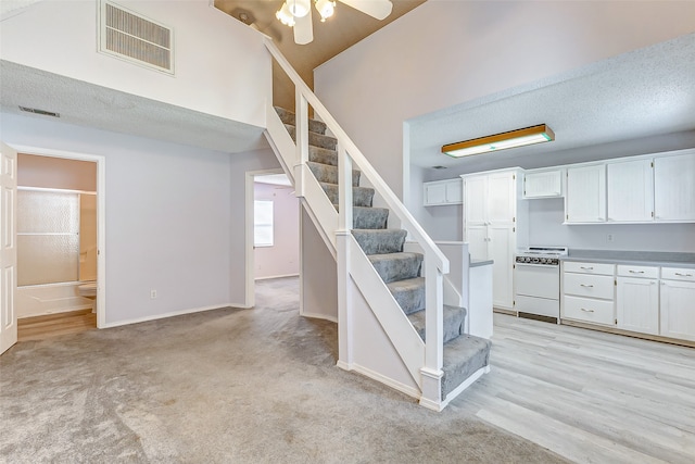 staircase with ceiling fan, carpet, and a textured ceiling