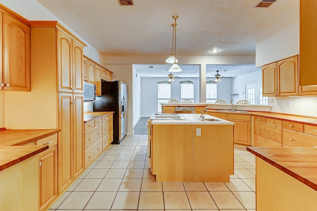 kitchen featuring a center island with sink, pendant lighting, a healthy amount of sunlight, and wooden counters