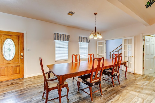 dining room featuring beam ceiling, an inviting chandelier, and light hardwood / wood-style flooring