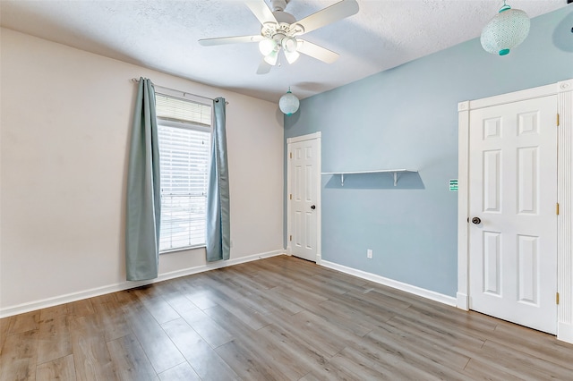 empty room featuring ceiling fan, a textured ceiling, and light wood-type flooring