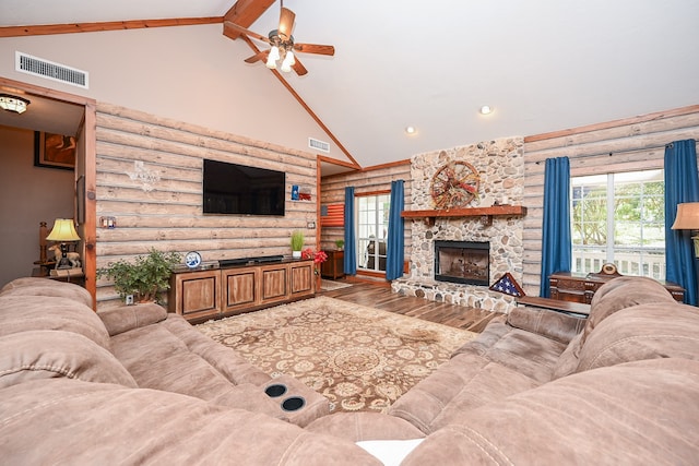 living room featuring hardwood / wood-style flooring, log walls, a stone fireplace, ceiling fan, and beam ceiling