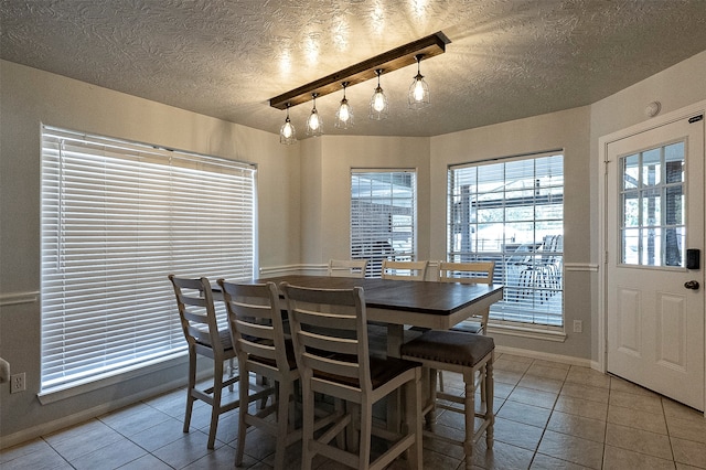 dining area featuring a textured ceiling, light tile patterned floors, and rail lighting