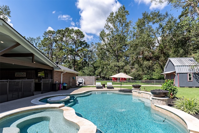 view of pool with a lawn, a patio, an in ground hot tub, and a shed