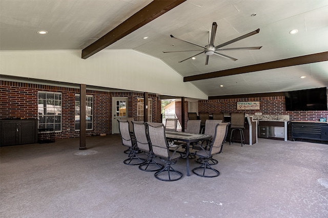 carpeted dining area with brick wall, vaulted ceiling with beams, and ceiling fan