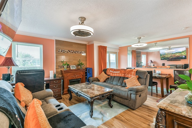 living room with wood walls, light hardwood / wood-style floors, crown molding, and a textured ceiling