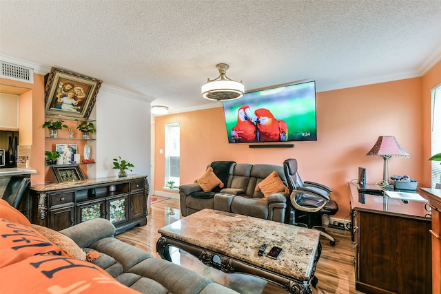 living room featuring a textured ceiling, a healthy amount of sunlight, ornamental molding, and light hardwood / wood-style flooring