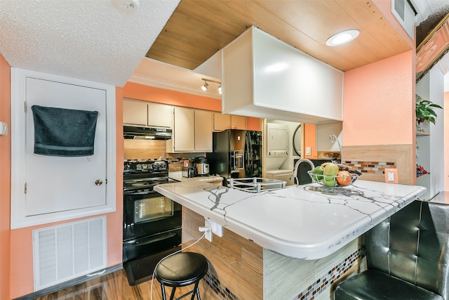 kitchen featuring a kitchen breakfast bar, black appliances, kitchen peninsula, decorative backsplash, and dark hardwood / wood-style floors