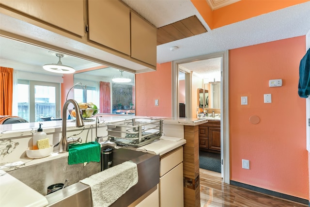 kitchen featuring ornamental molding, a textured ceiling, decorative light fixtures, and dark hardwood / wood-style floors