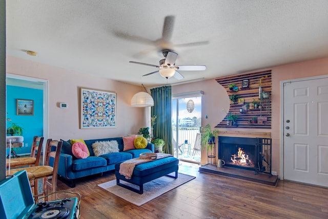 living room with a textured ceiling, ceiling fan, and dark wood-type flooring