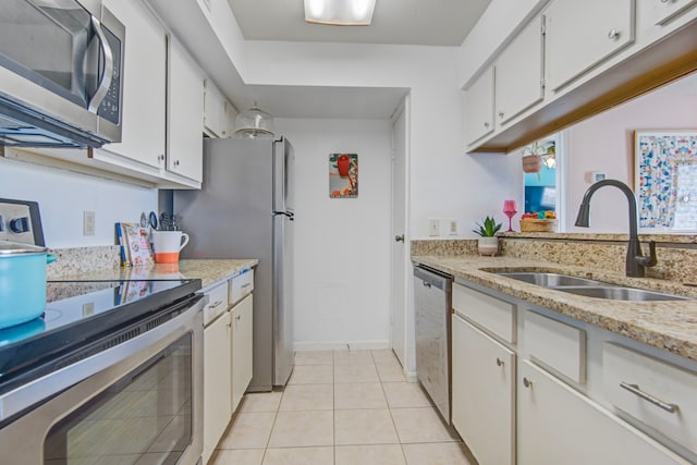 kitchen featuring light stone countertops, stainless steel appliances, sink, light tile patterned floors, and white cabinetry