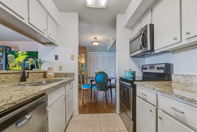 kitchen featuring sink, light stone counters, light hardwood / wood-style floors, white cabinets, and appliances with stainless steel finishes