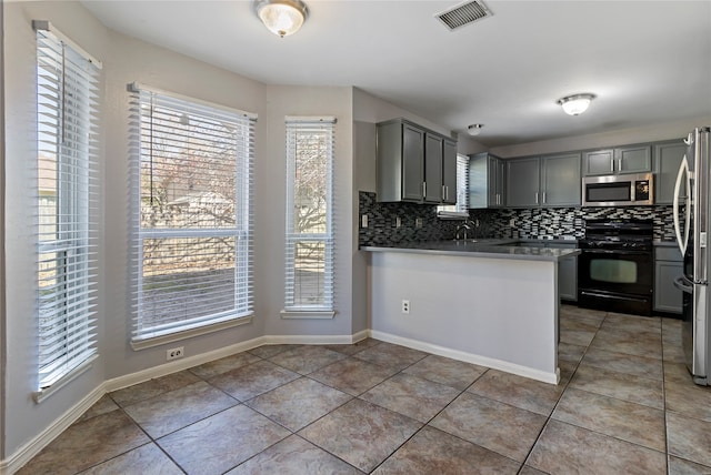 kitchen featuring tasteful backsplash, stainless steel appliances, kitchen peninsula, and a healthy amount of sunlight