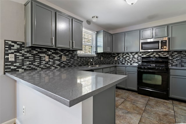 kitchen featuring gray cabinetry, black gas range oven, backsplash, and kitchen peninsula