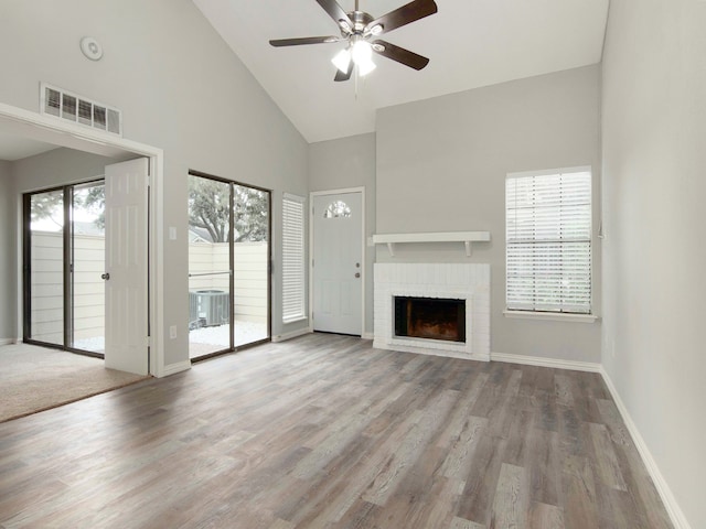 unfurnished living room with plenty of natural light, ceiling fan, and a brick fireplace