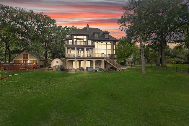 back house at dusk with a lawn and a deck