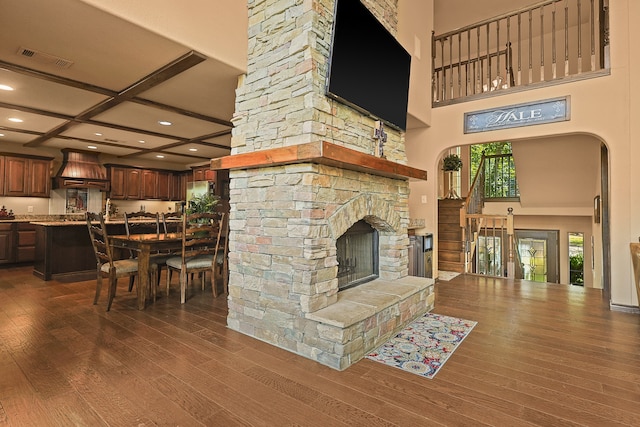 living room with coffered ceiling, dark hardwood / wood-style floors, beam ceiling, and a fireplace