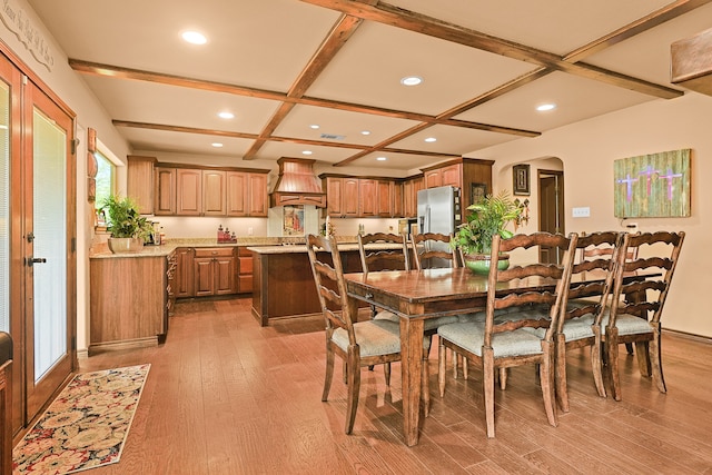 dining area with light wood-type flooring, coffered ceiling, and beamed ceiling