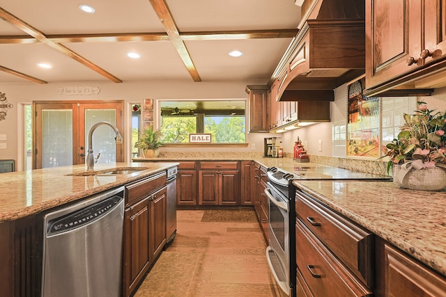 kitchen featuring light stone countertops, premium range hood, stainless steel appliances, sink, and light wood-type flooring