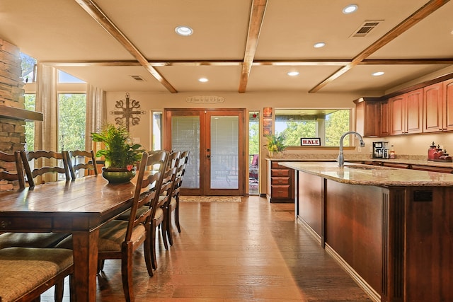 kitchen with light stone counters, sink, dark wood-type flooring, a stone fireplace, and french doors