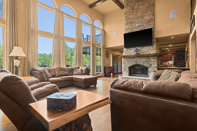 living room featuring light hardwood / wood-style flooring, a towering ceiling, and a stone fireplace