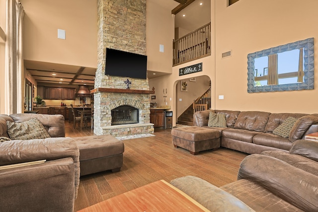 living room with a high ceiling, wood-type flooring, and a fireplace