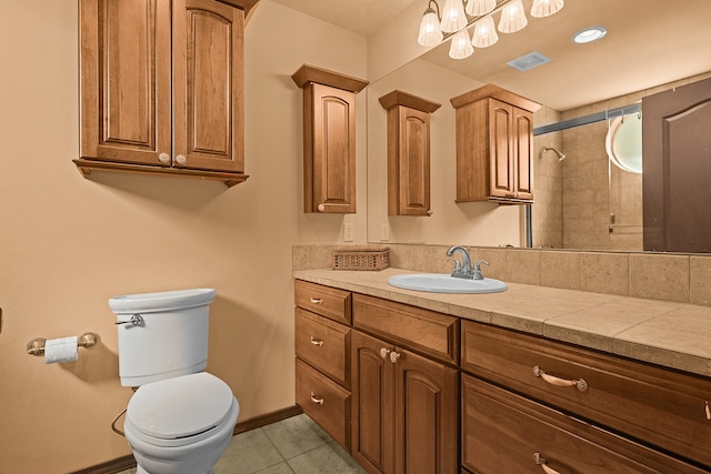 bathroom with tiled shower, vanity, toilet, and tile patterned flooring