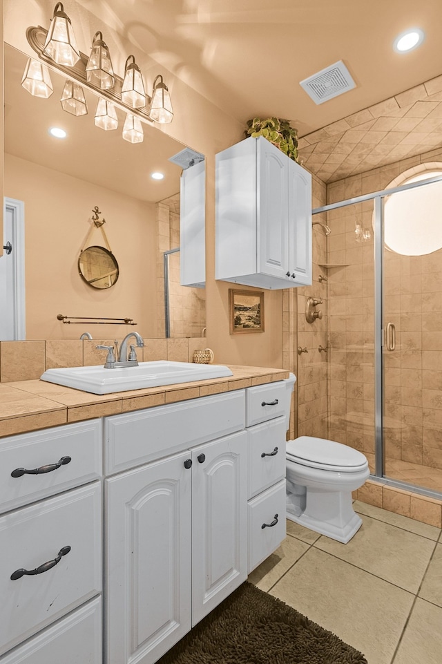 bathroom featuring tile patterned flooring, vanity, toilet, and a shower with door