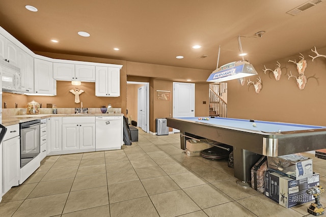 kitchen with pool table, white appliances, light tile patterned floors, hanging light fixtures, and white cabinetry