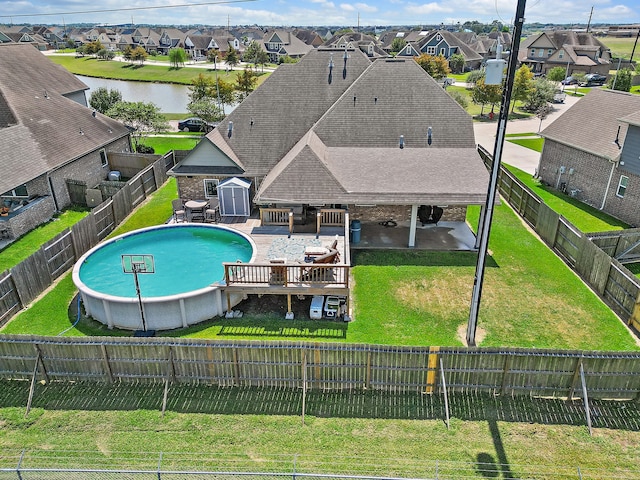 view of swimming pool with a deck with water view, a yard, a patio, and a storage shed