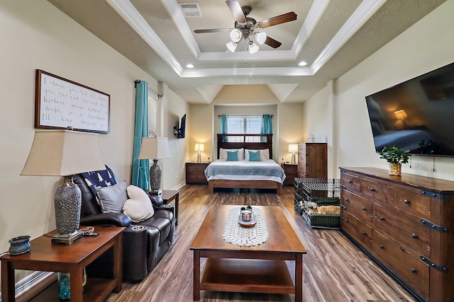 bedroom featuring a raised ceiling, ceiling fan, light hardwood / wood-style flooring, and crown molding