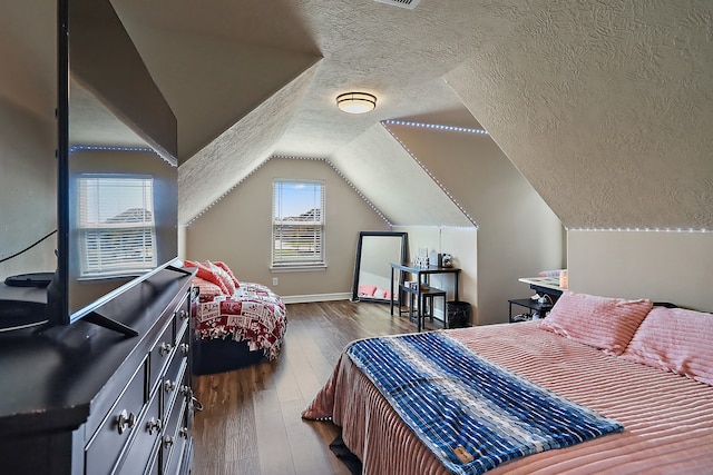 bedroom with a textured ceiling, vaulted ceiling, and dark wood-type flooring