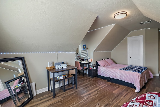 bedroom featuring a textured ceiling, dark hardwood / wood-style flooring, and vaulted ceiling