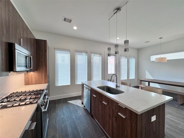 kitchen featuring hanging light fixtures, appliances with stainless steel finishes, plenty of natural light, sink, and a kitchen island with sink