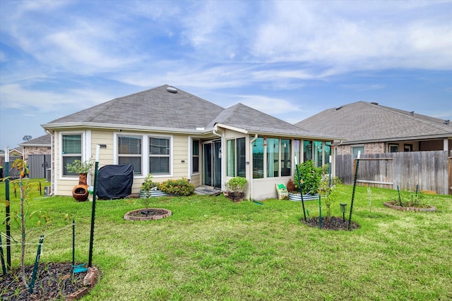 back of house featuring a sunroom, a yard, and an outdoor fire pit