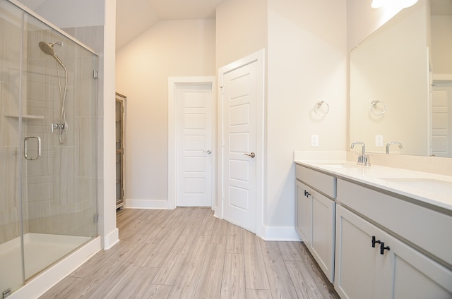 bathroom with hardwood / wood-style floors, vanity, vaulted ceiling, and a shower with door