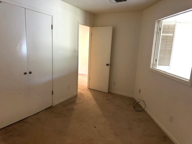 unfurnished bedroom with light carpet and a closet