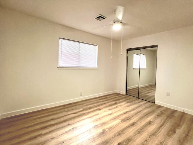 unfurnished bedroom featuring visible vents, a ceiling fan, wood finished floors, a closet, and baseboards